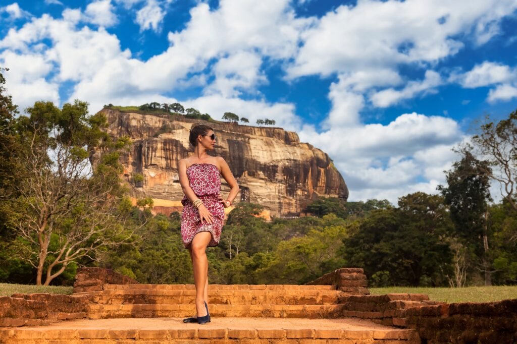 Young woman in sunglasses posing in front Sigiriya rock fortress at Sri Lankan sight