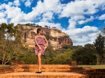 Young woman in sunglasses posing in front Sigiriya rock fortress at Sri Lankan sight